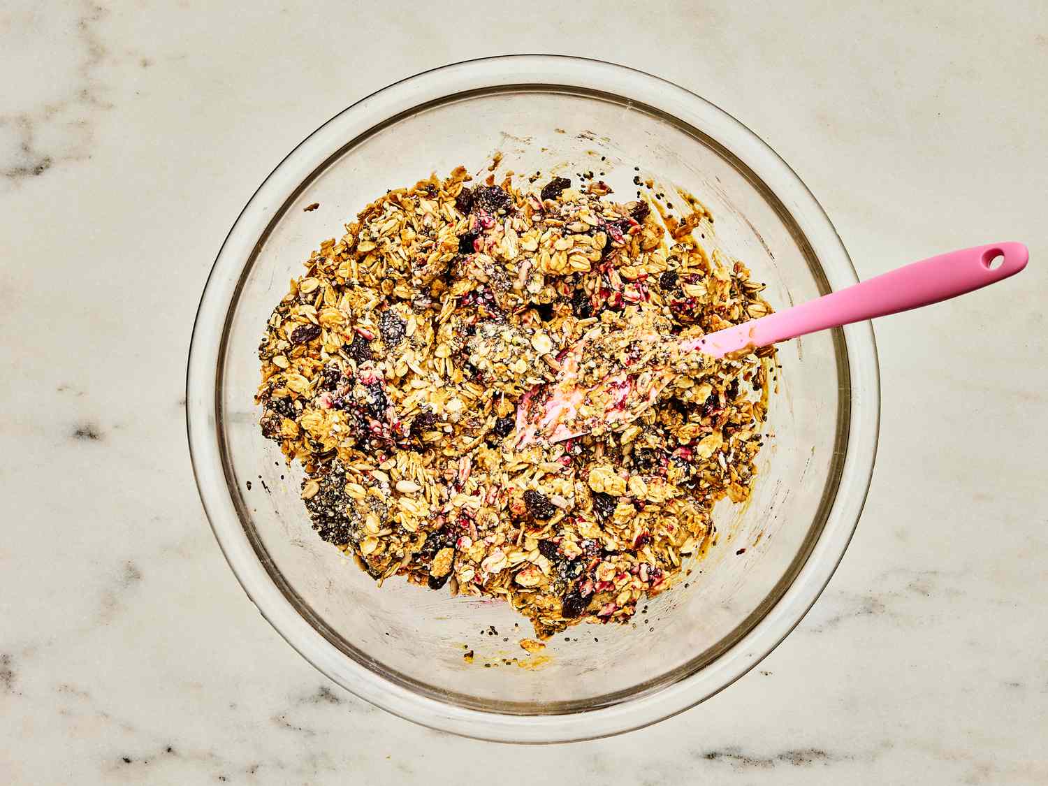 Cooled oats, nut butter, dried fruit, chia seends, hemp seeds, sunflower kernels, fruit preserves and salt mixed together in a large glass bowl