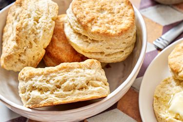 A bowl and plate containing freshly baked buttermilk biscuits