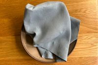 A folded cloth draped over a ceramic dish on a wooden surface