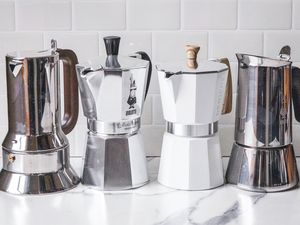 Four moka pots lined up on a kitchen counter