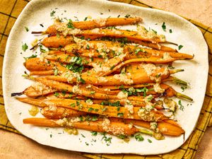 A dish of roasted carrots topped with herbs and a glaze