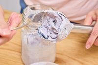 A person spoons pureed food from the Vitamix Immersion Blender blade