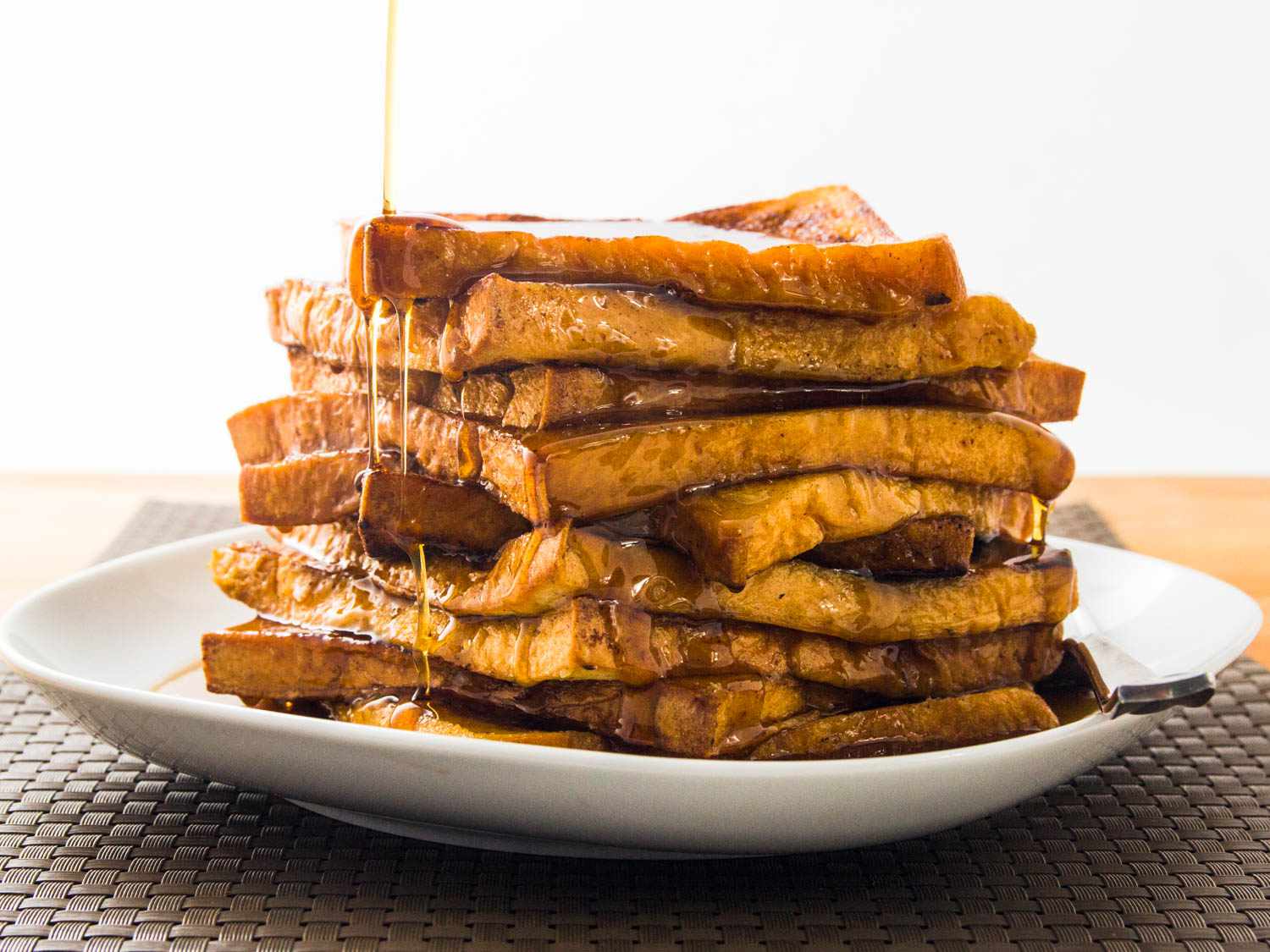 A tall stack of French toast drizzled with syrup.