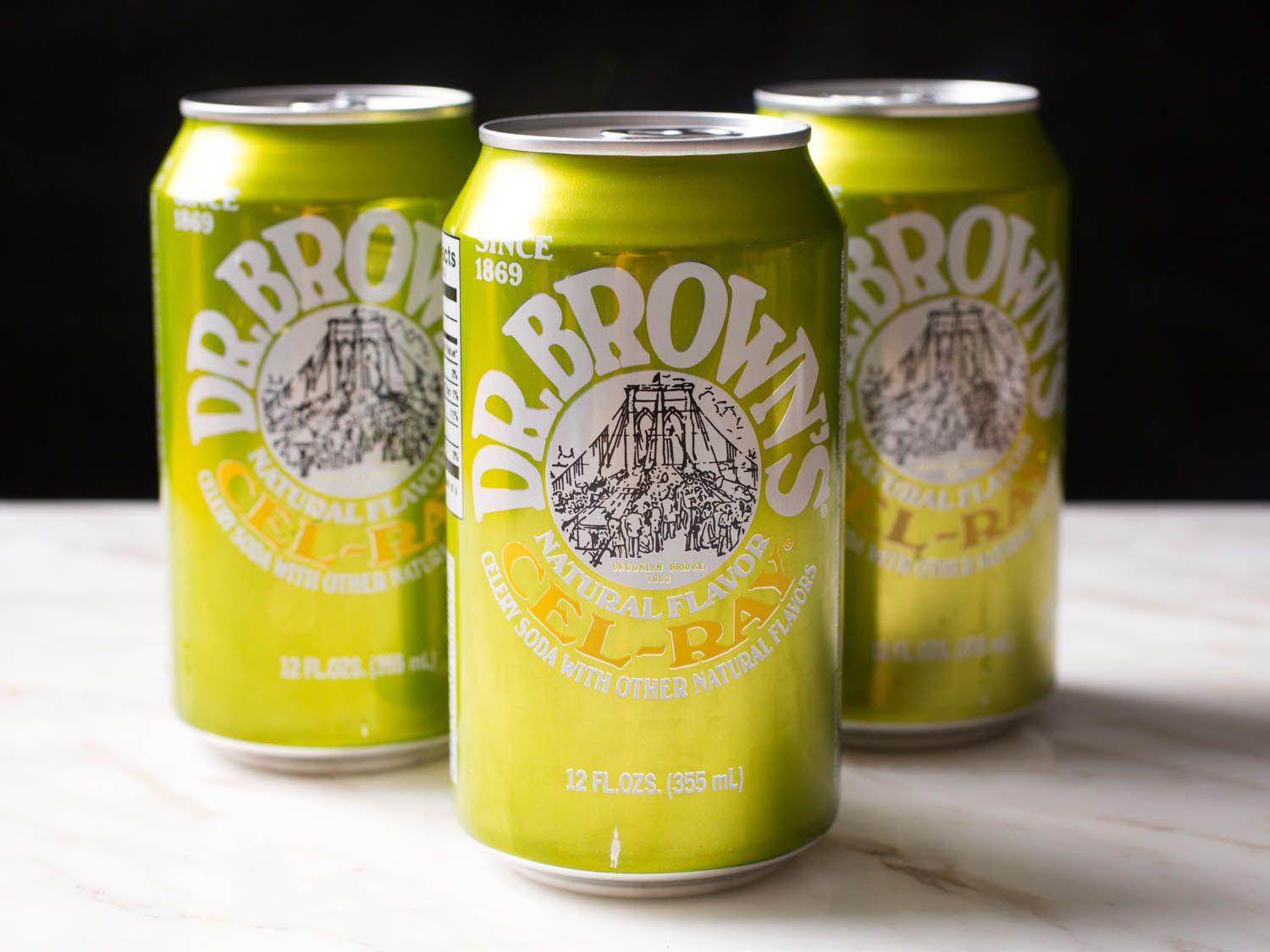 Three cans of Dr. Brown's Cel-Ray soda on a counter.