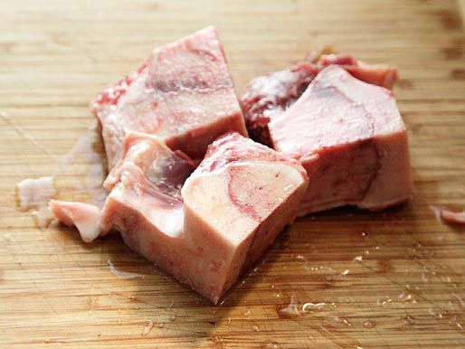 Beef leg bone on a wooden cutting board. 