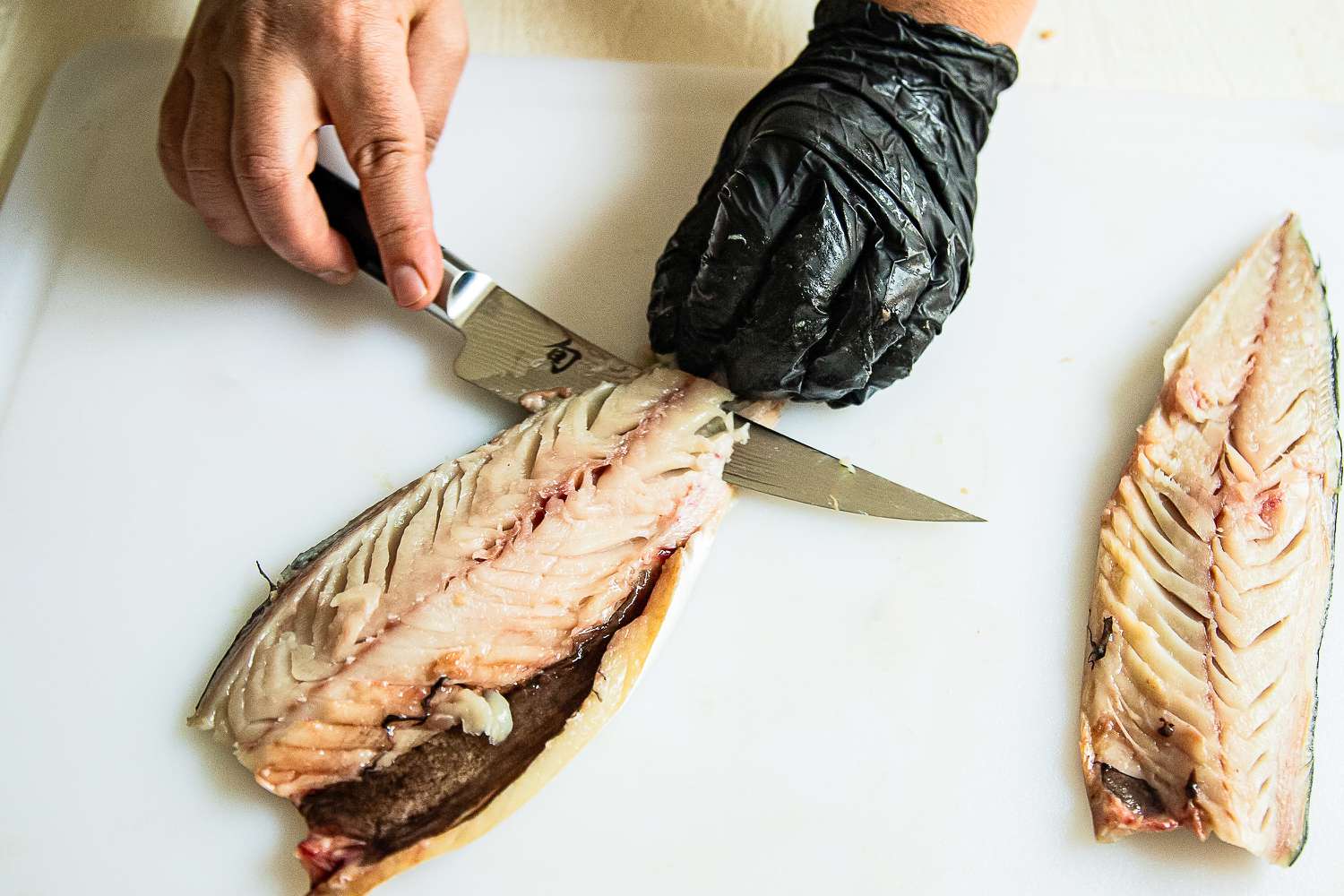 A person using the Shun Classic 6" Boning & Fillet Knife to slice a fish