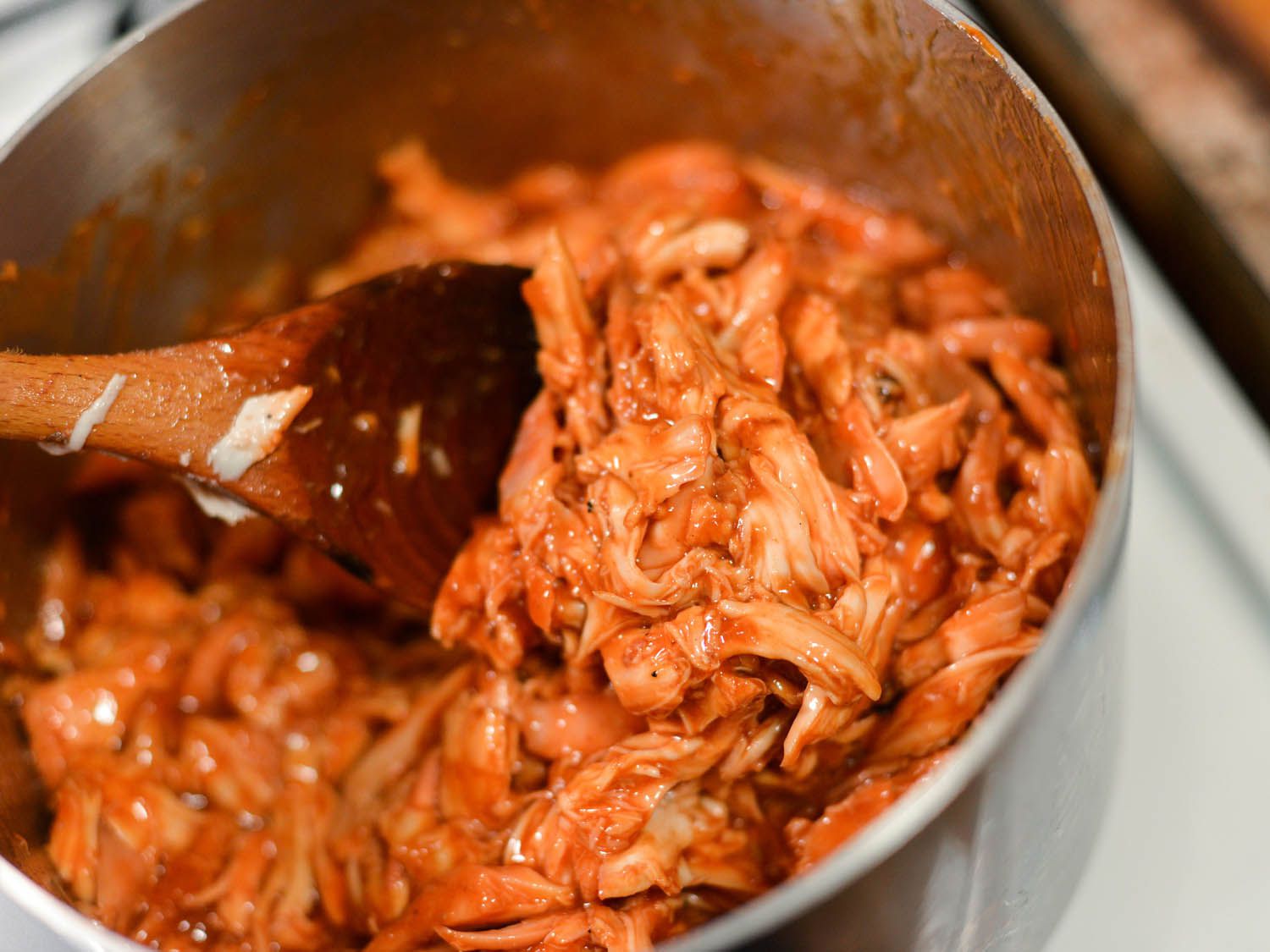 Closeup of the chicken being tossed with sauce in a saucepan.