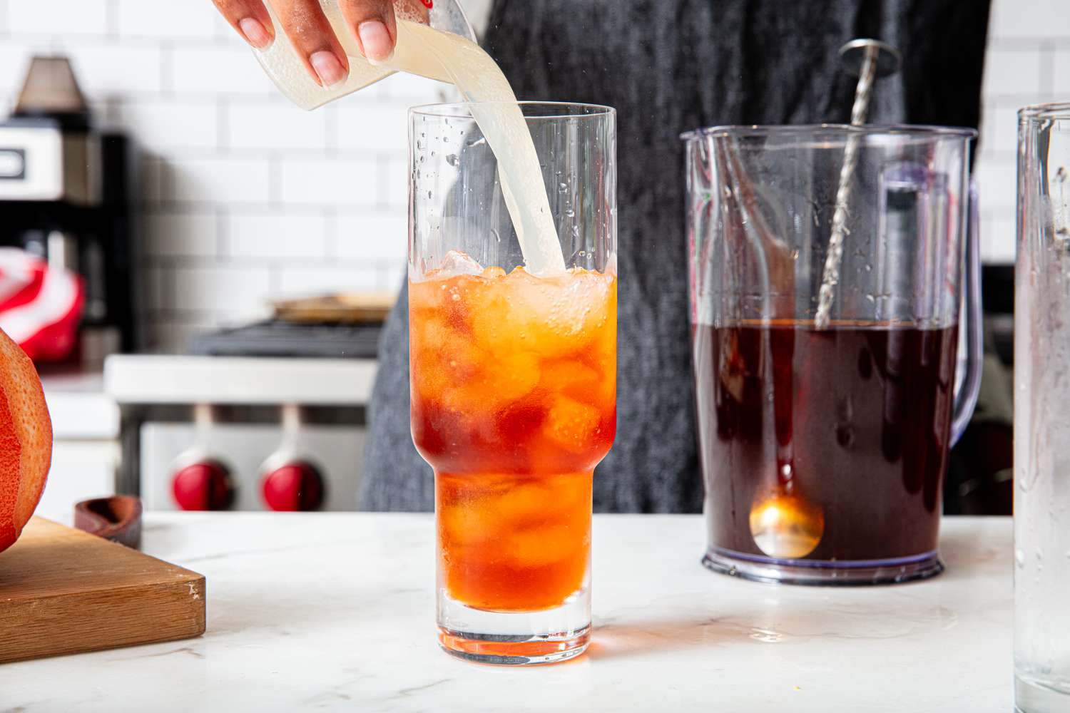 Pouring grapefruit soda into an Apposta cocktail in a glass