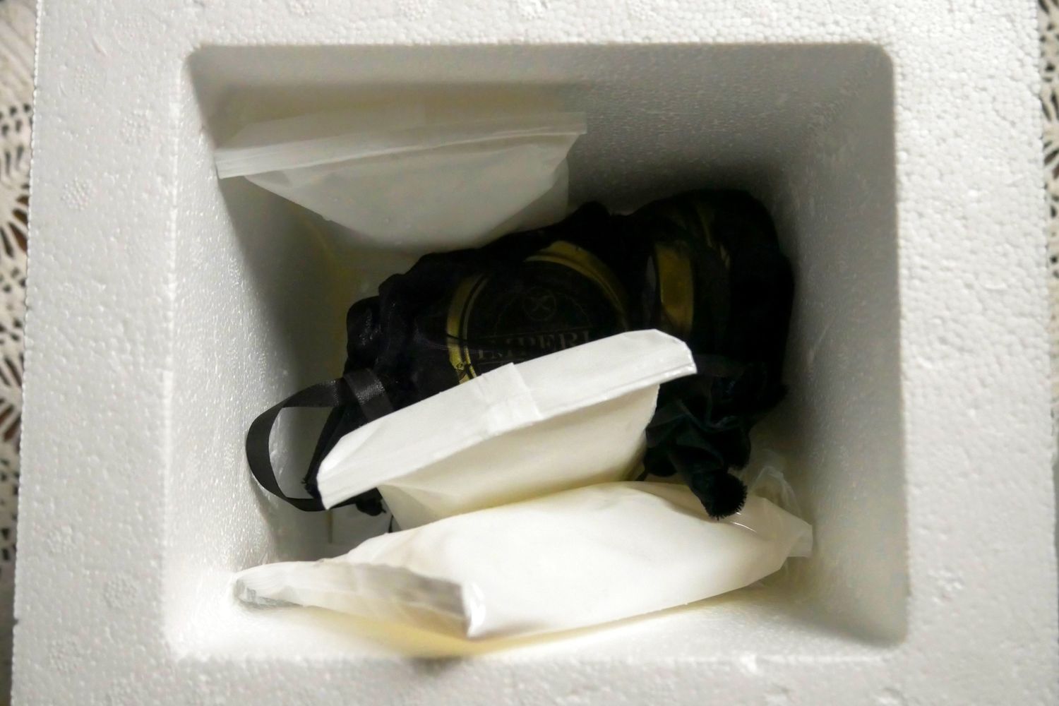 A small white container with sealed bags inside placed on a textured surface