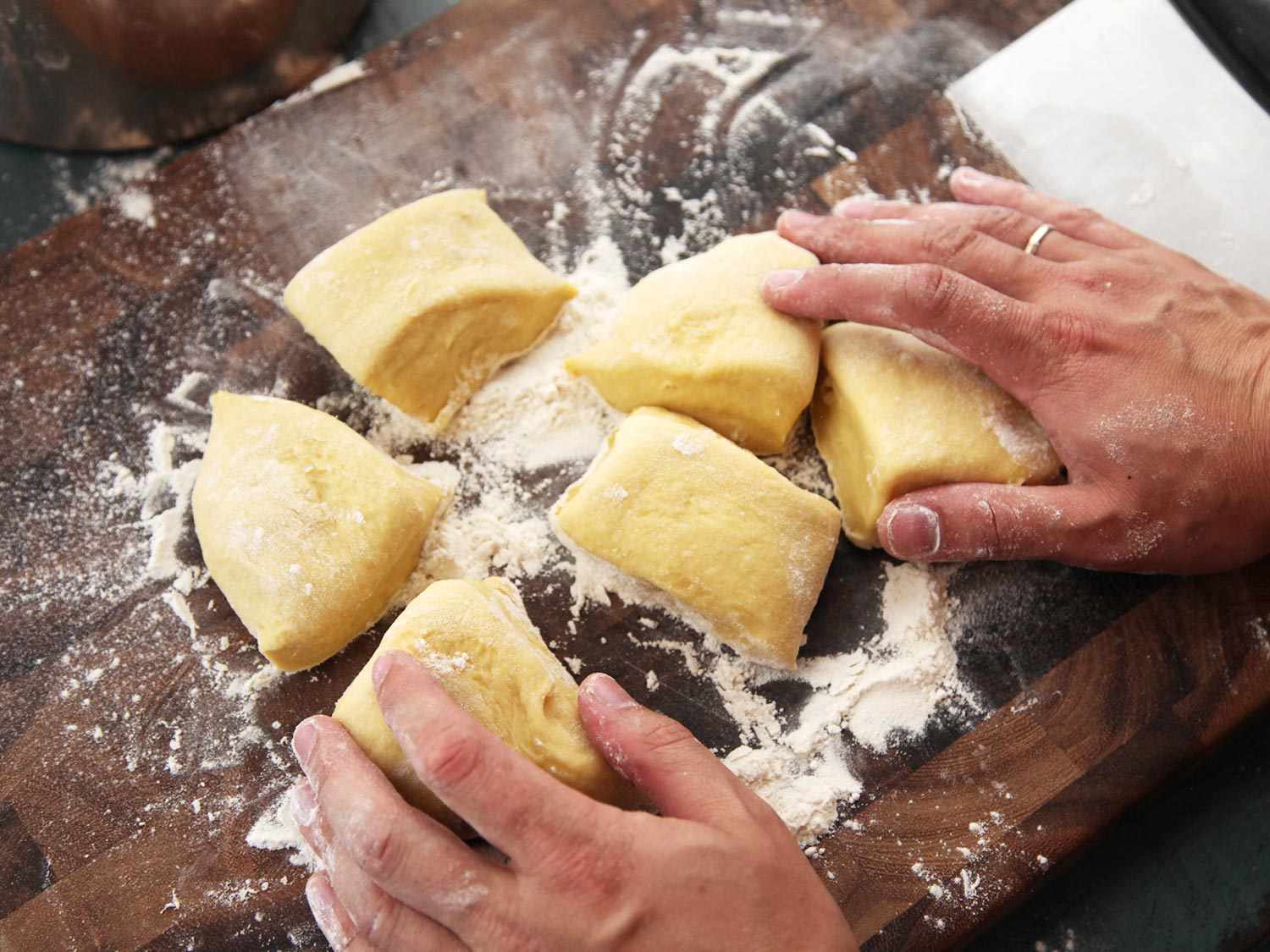 Overhead view of a cutting board with the cut portions of cemita dough.