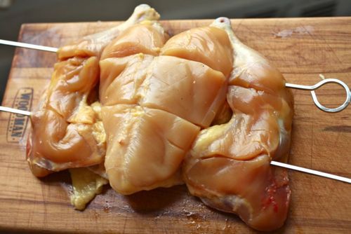 Skewering through a Cornish hen with metal skewers.