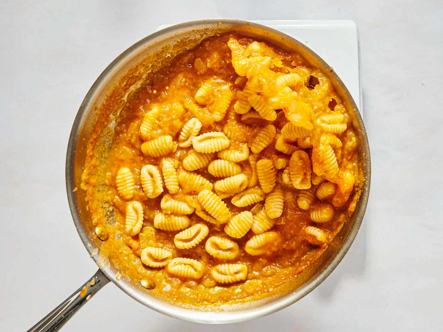 mixing pasta into pan with sauce