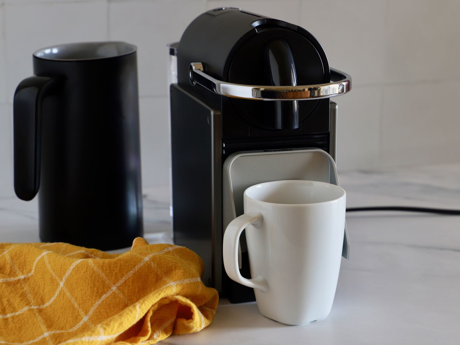 A Nespresso Pixie machine with its cup shelf flipped up to fit a mug underneath the spout.