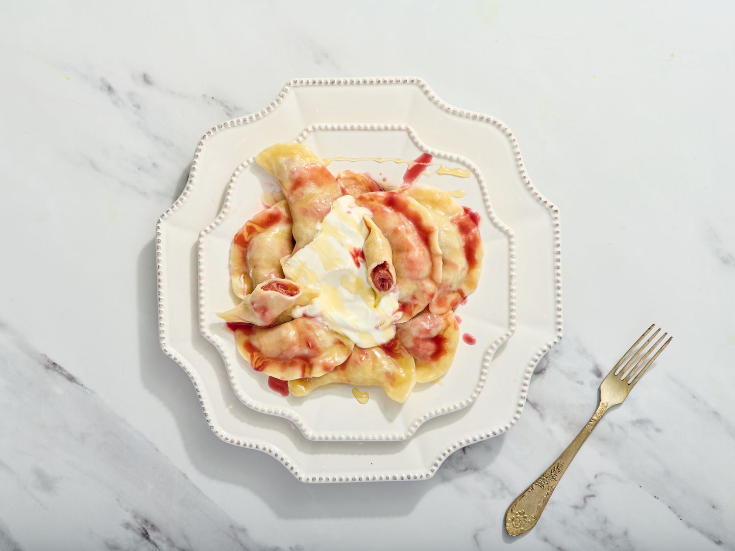 Plate of varenyky with cream and honey, with fork on the side 