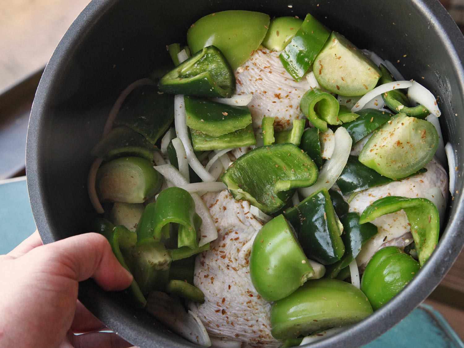 Pressure cooker insert with raw peppers, tomatillos, and onions for chicken green chili (chile verde).
