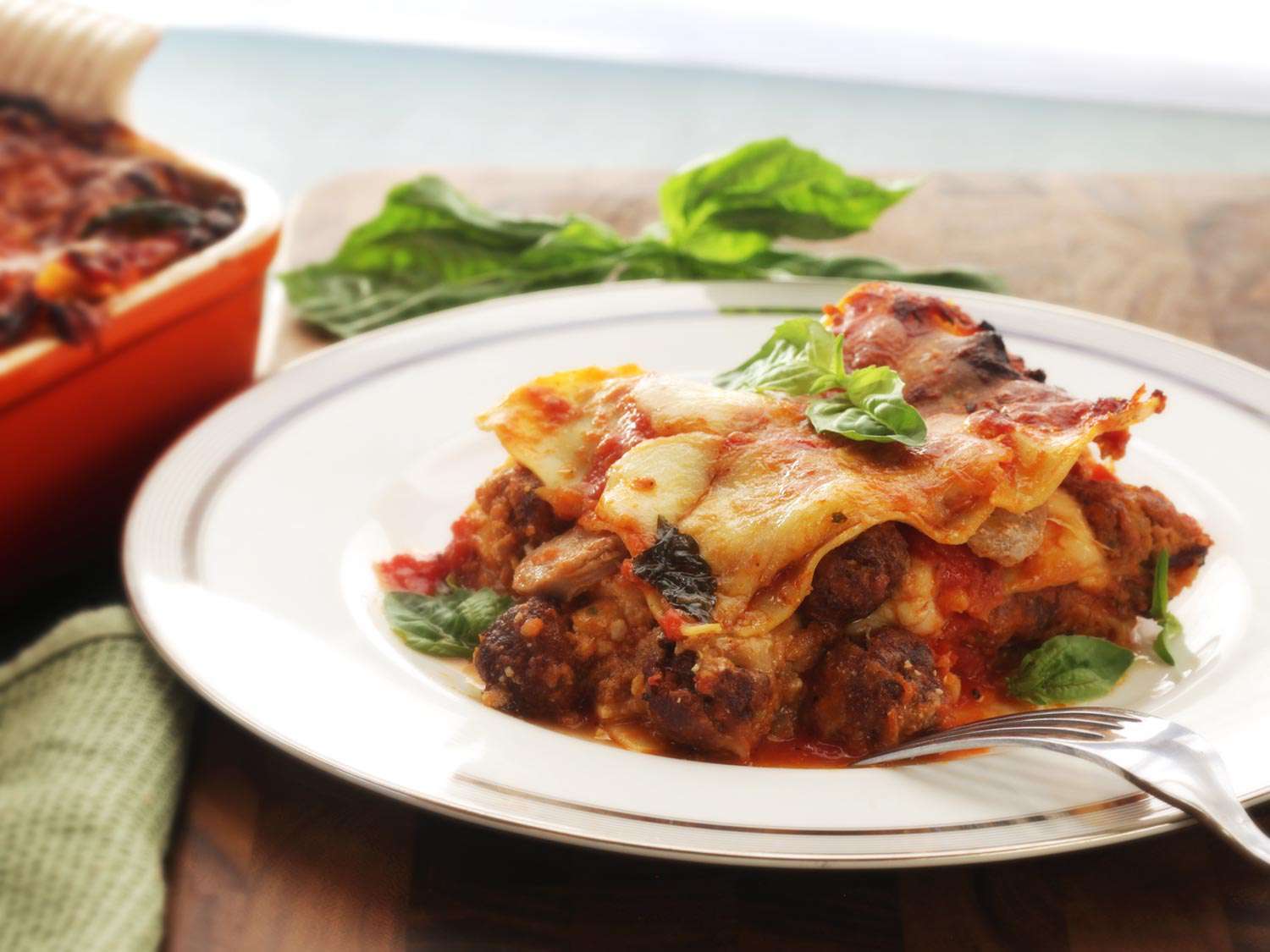 Lasagna Napoletana plated and garnished with with fresh basil leaves