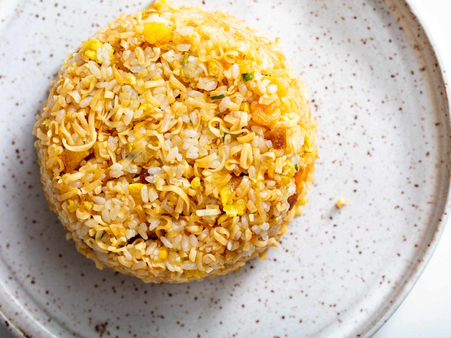 Overhead close-up of the finished instant ramen fried rice on a speckled earthenware plate.