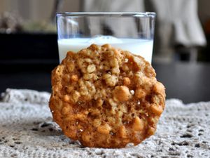 A coconut scotchy cookie, propped up against a glass of milk.
