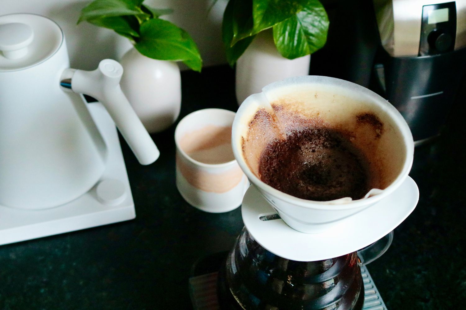 A spent filter sitting in a pourover with a full carafe of coffee below it