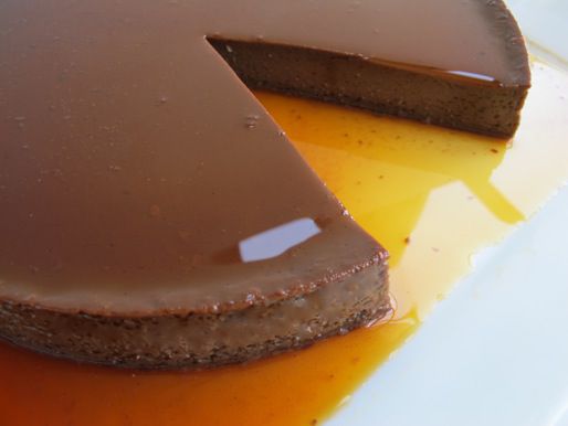 Close-up of Mexican chocolate flan. A slice is missing and the caramel sauce has pooled below on the serving plate.