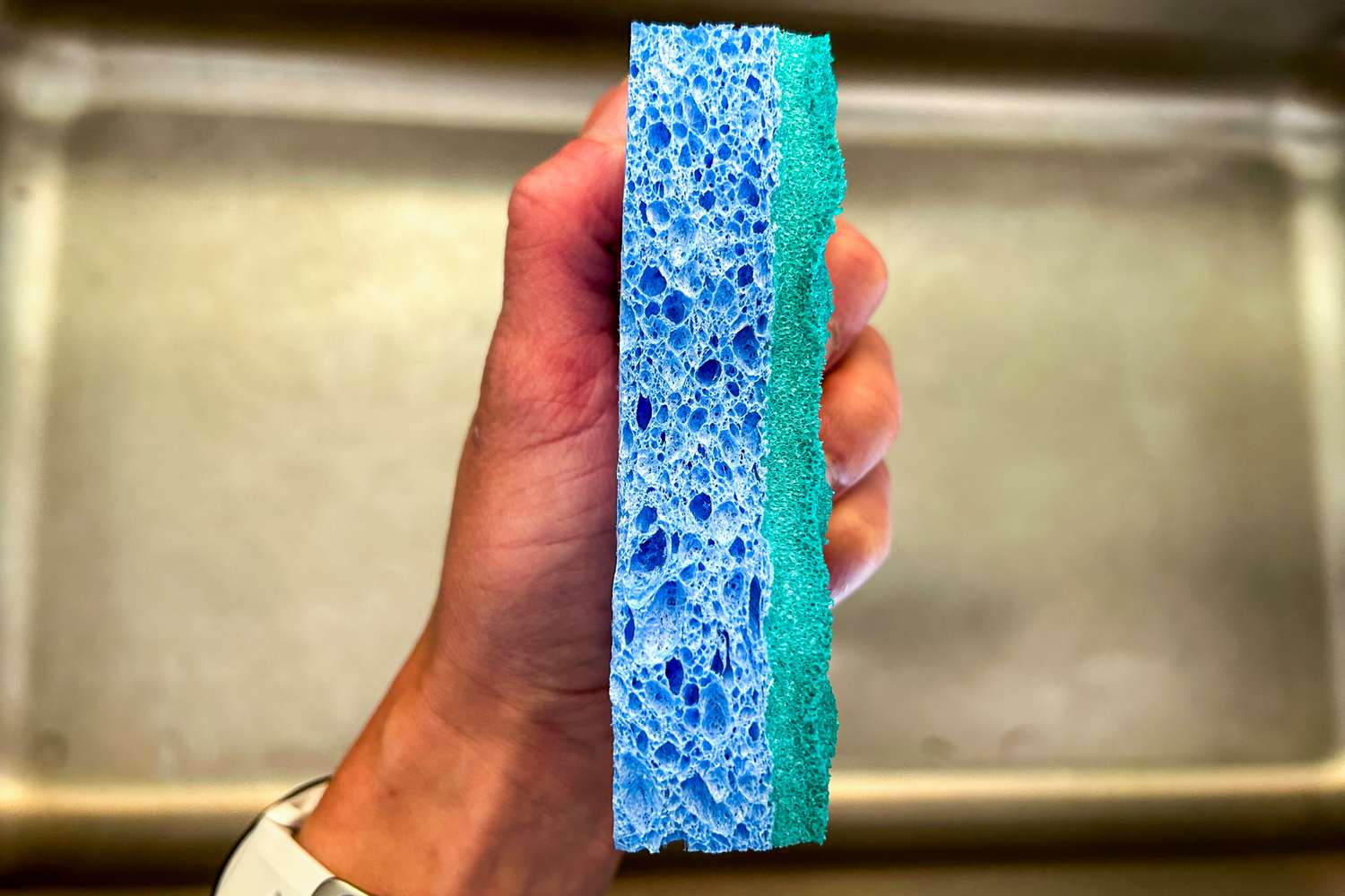 An O-Cedar Scrunge being held over a stainless steel sink