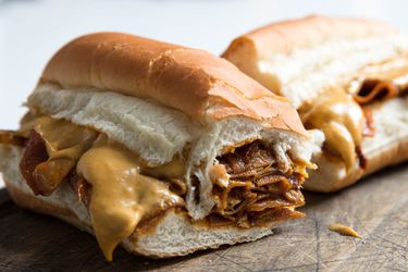 A vegan cheesesteak cut in half with vegan cheese dripping out 
