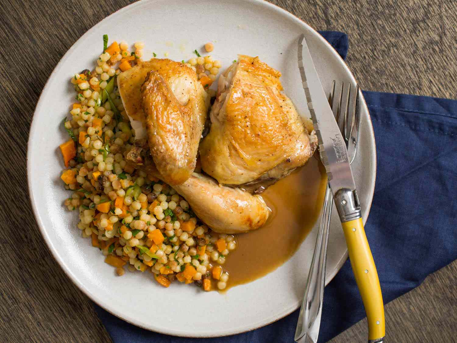 Roast chicken and jus plated with warm fregola and butternut squash salad 