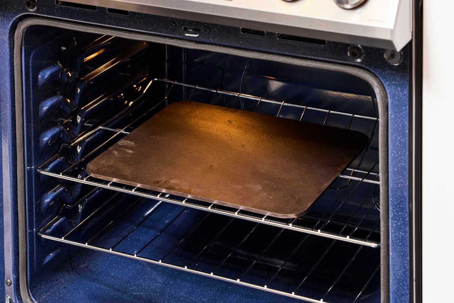 A pizza steel on an oven's rack.