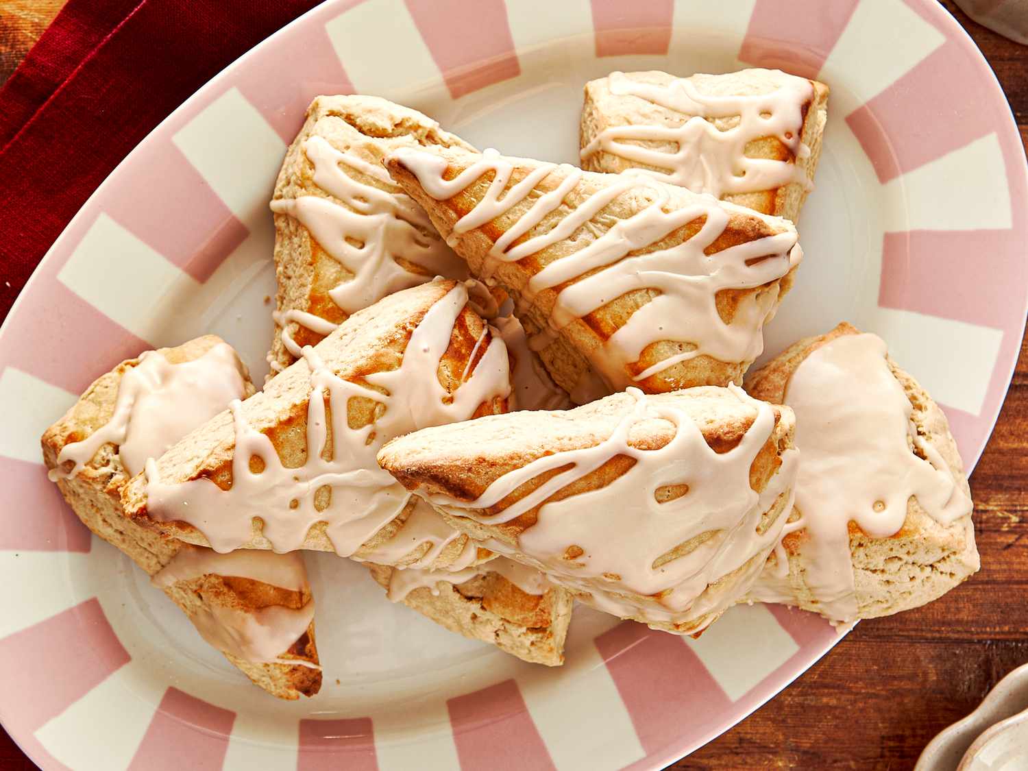 A plate of scones with an icing drizzle arranged on a striped dishware plate