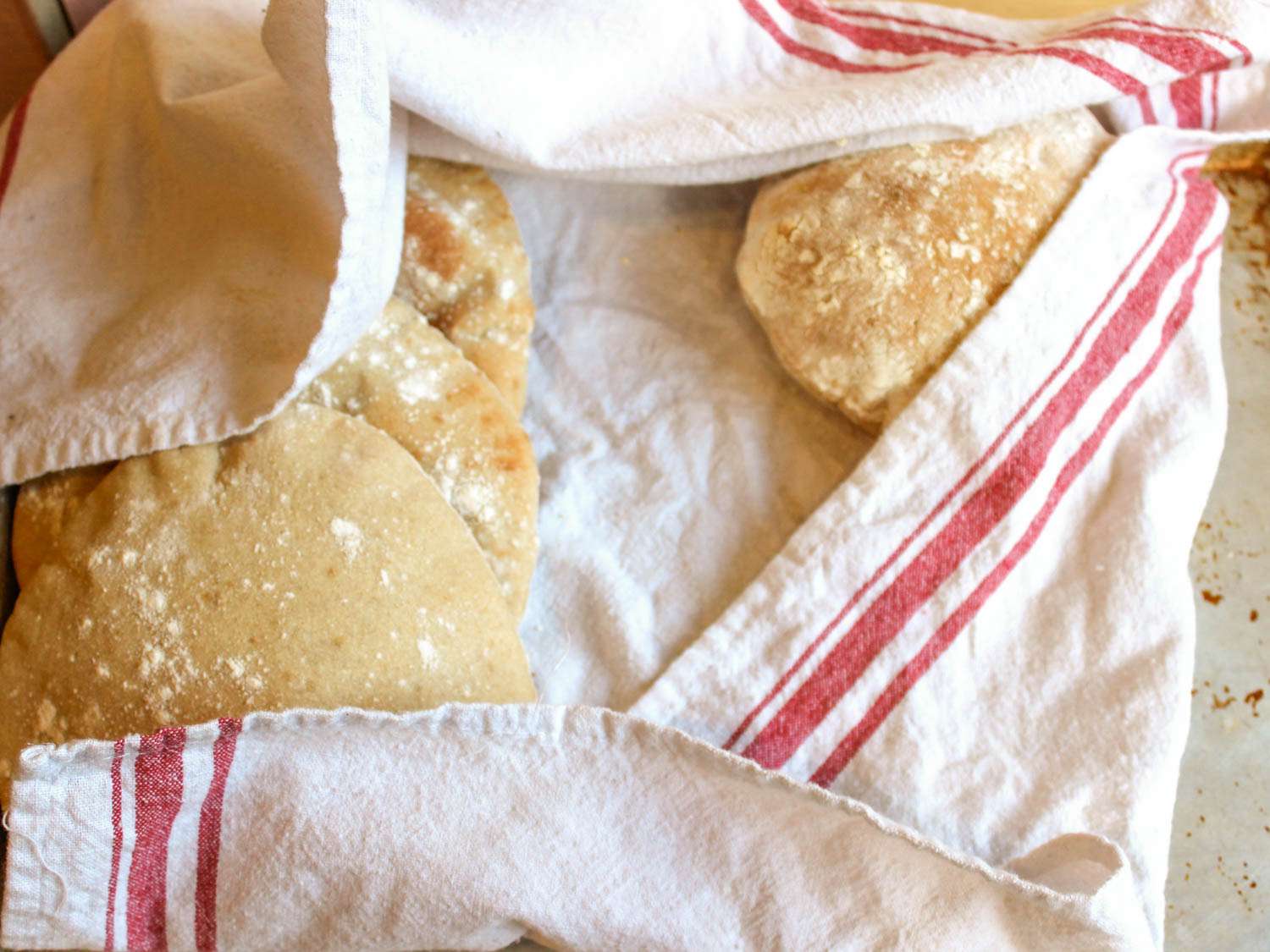 Freshly baked homemade pita wrapped in a kitchen towel.