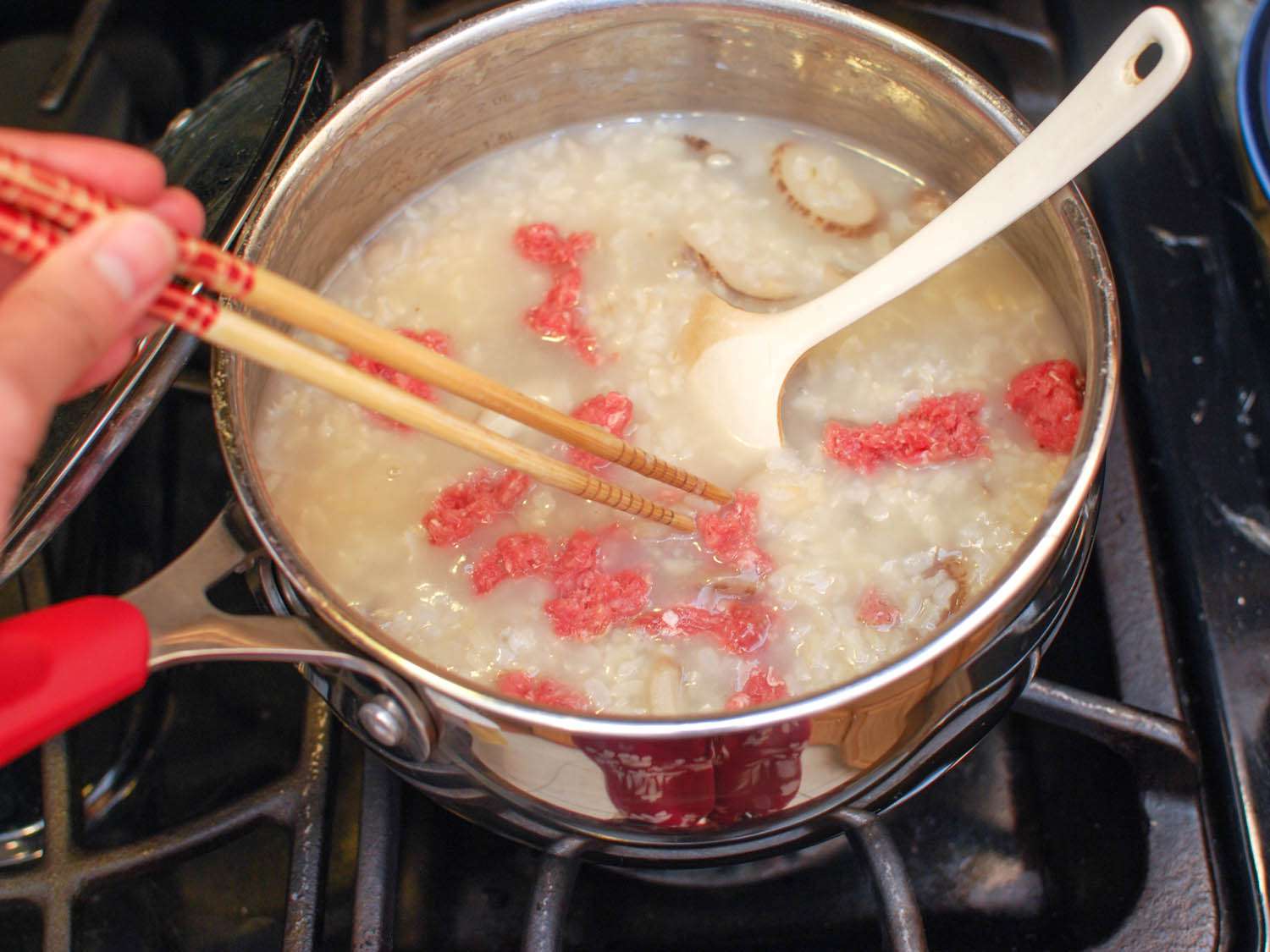 Teaspoon-sized chunks of the marinated ground beef are added to the congee with chopsticks.