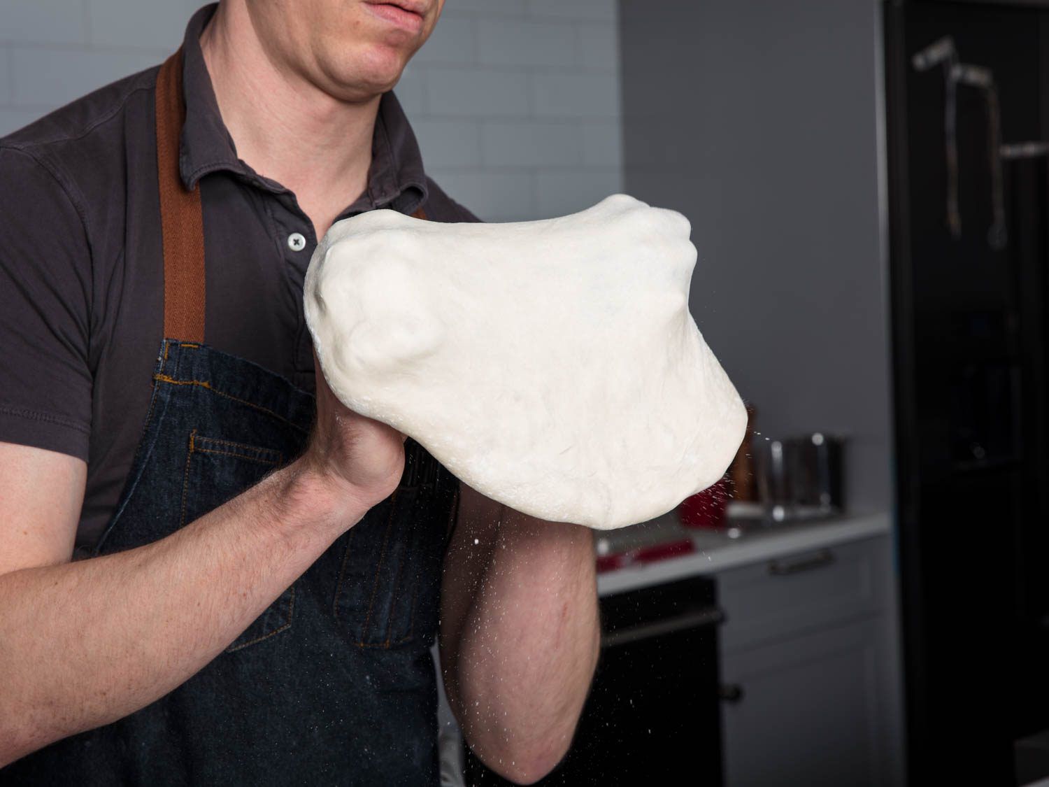 Stretching pizza dough with knuckles.