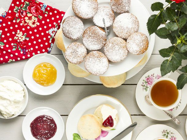 A table full of different British sweets and a cup of tea. 