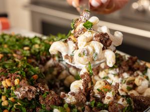Plate of pasta with ground beef and herbs being served