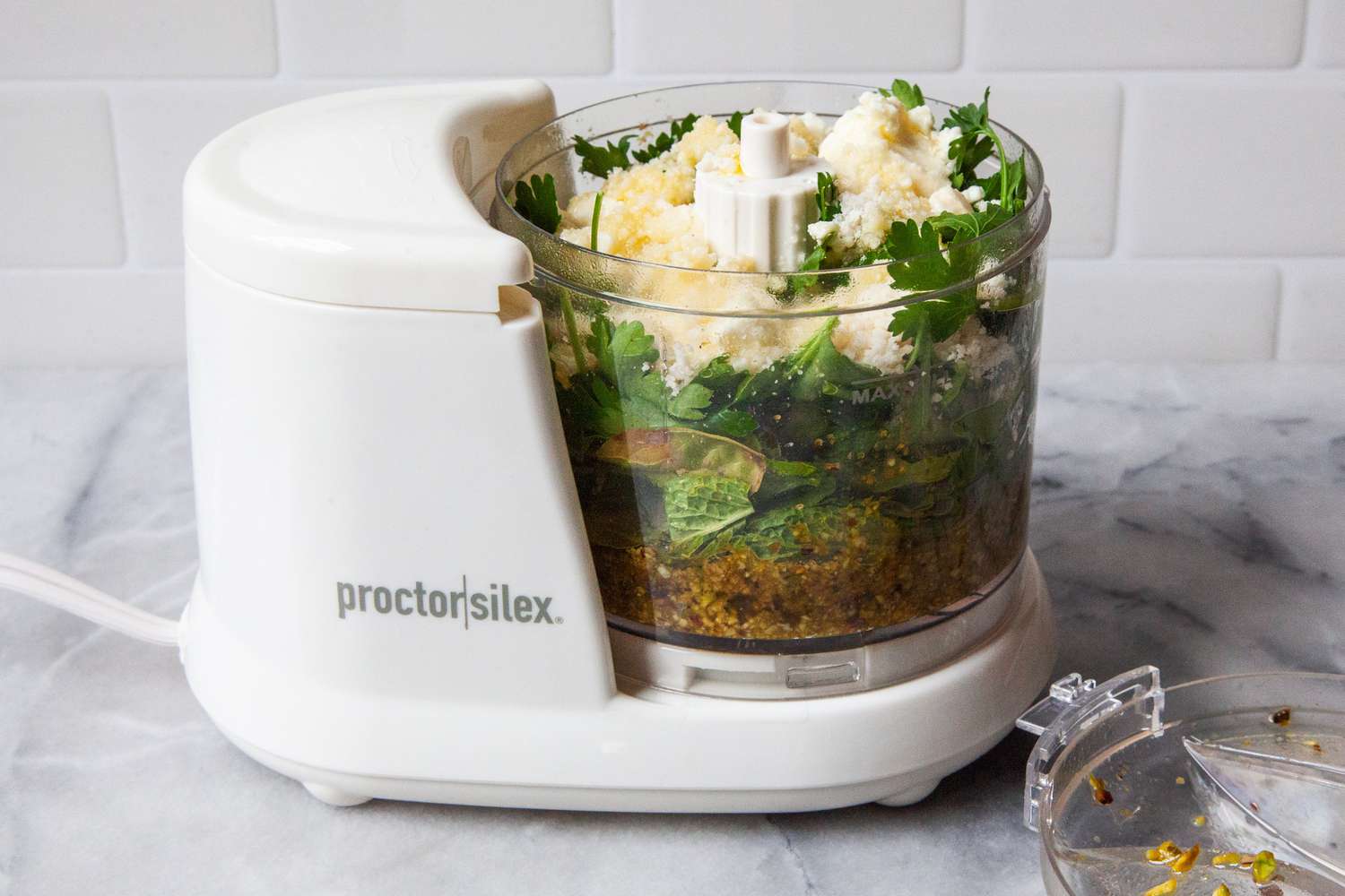 Pesto ingredients in the bowl of a mini food processor.