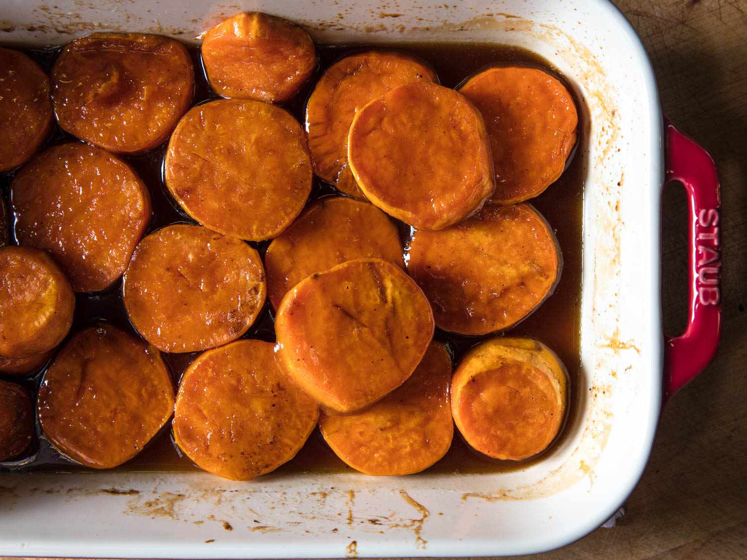 Candied yams (sweet potatoes) baked in a red Staub baking dish.