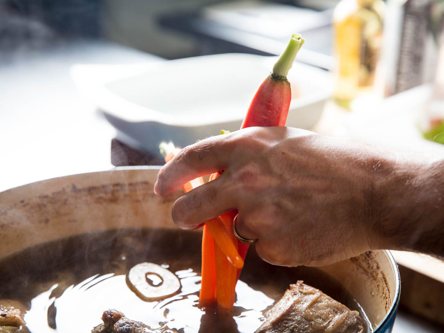 Adding a carrot to a Dutch oven.