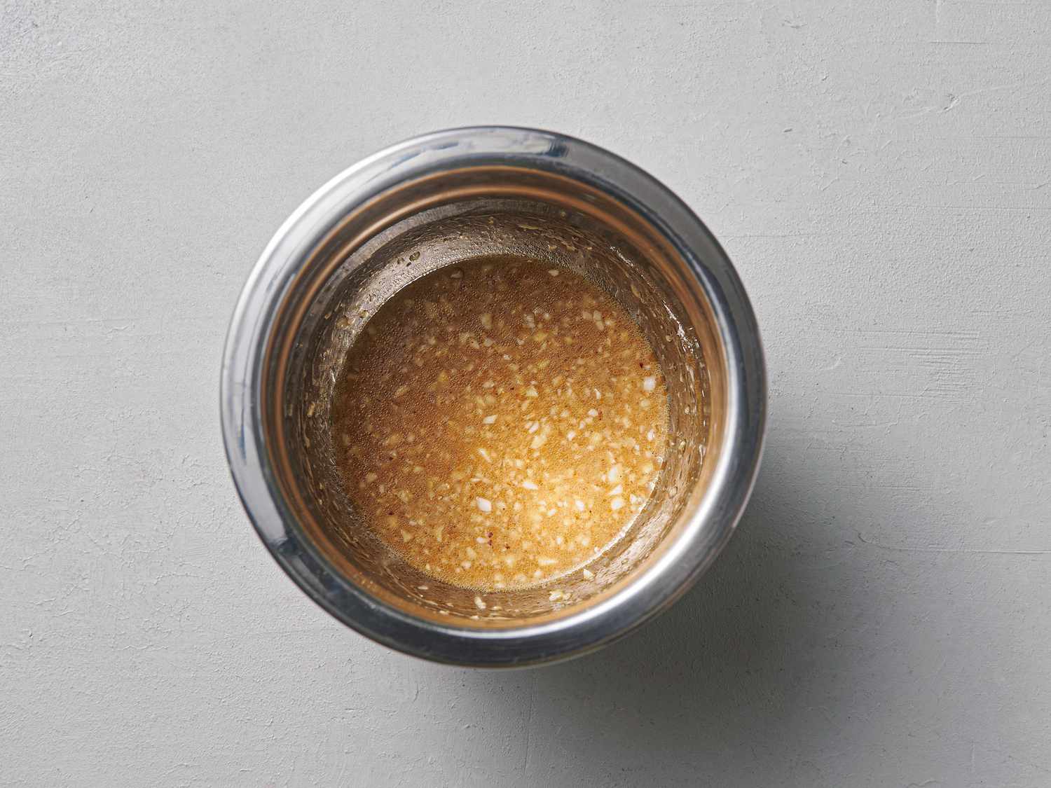 Garlic added to ground white pepper powder and other ingredients, mixed inside small bowl