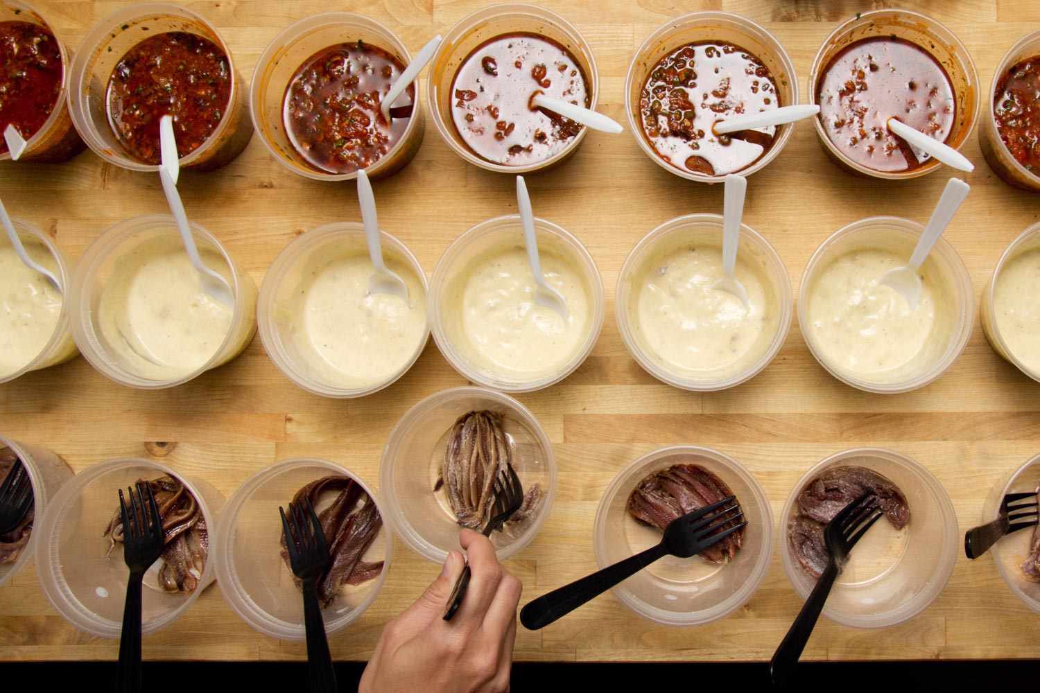 An overhead view of Caesar salad dressing, puttanesca sauce, and plain anchovies.