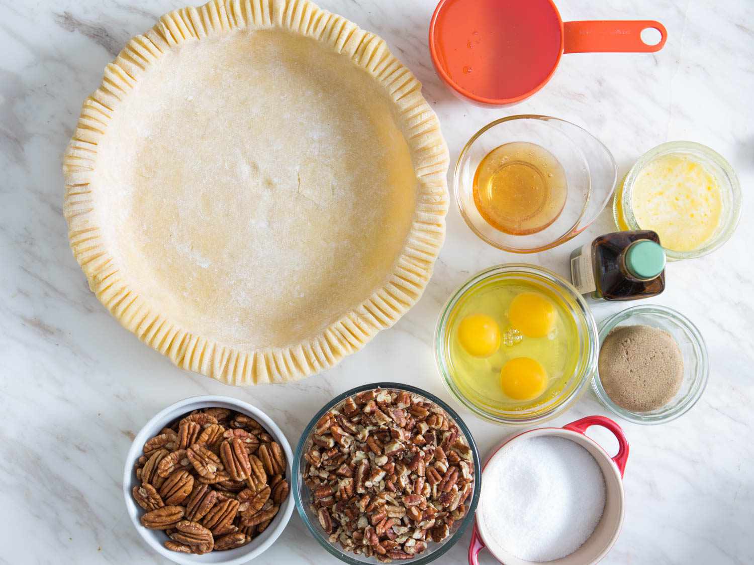 Overhead shot of unbaked pie crust and filling ingredients for pecan pie.