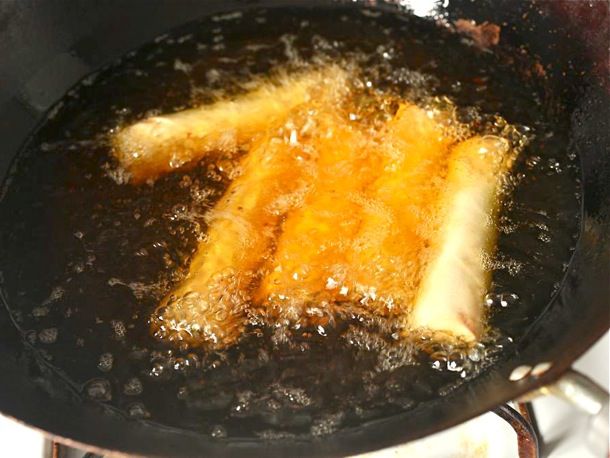 The egg rolls are deep fried in a wok.