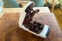 The OXO Good Grips Quick Release Multi Cherry Pitter on a wooden cutting board
