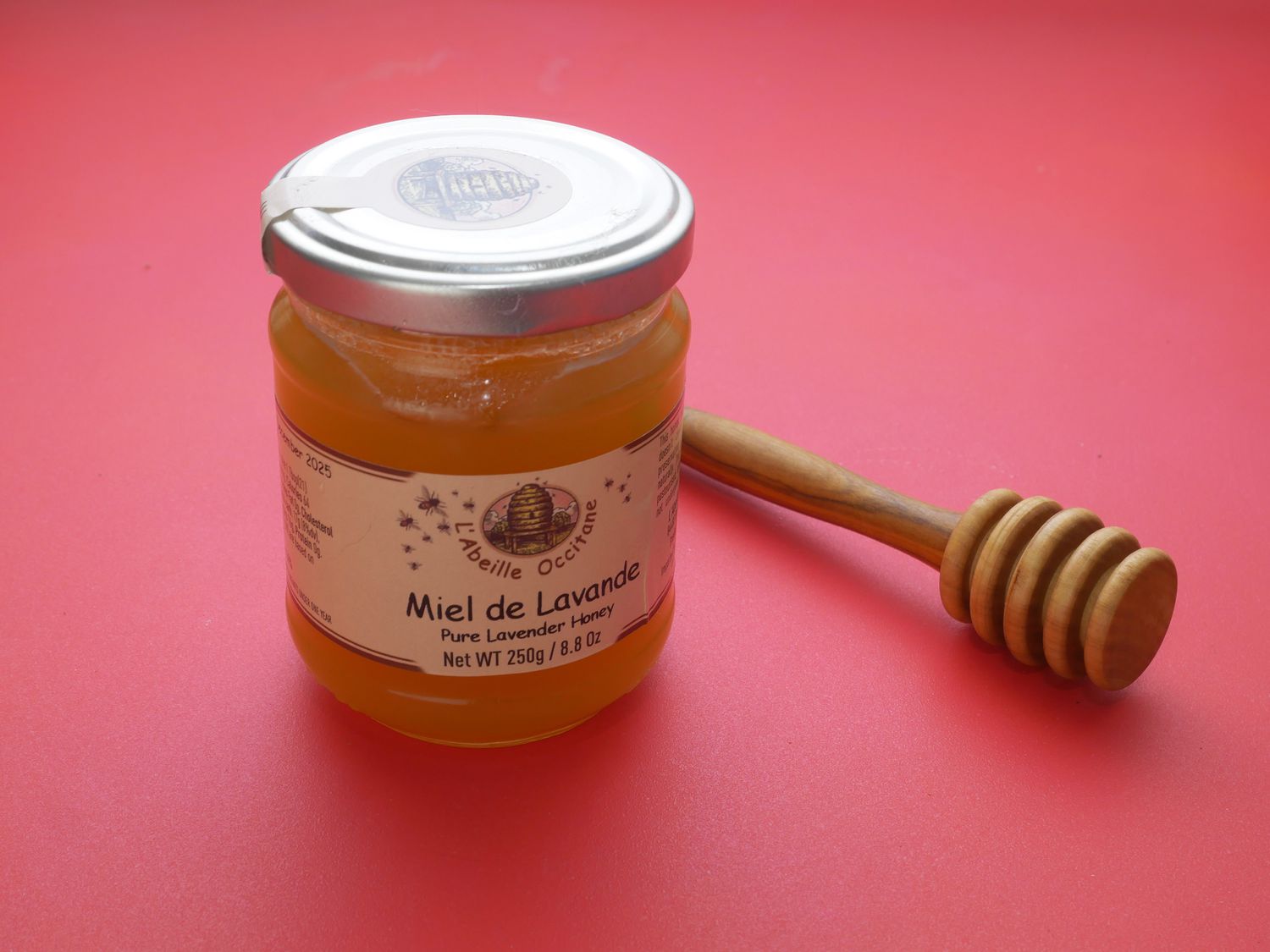 lavender honey on red backdrop with honey dripper to the side