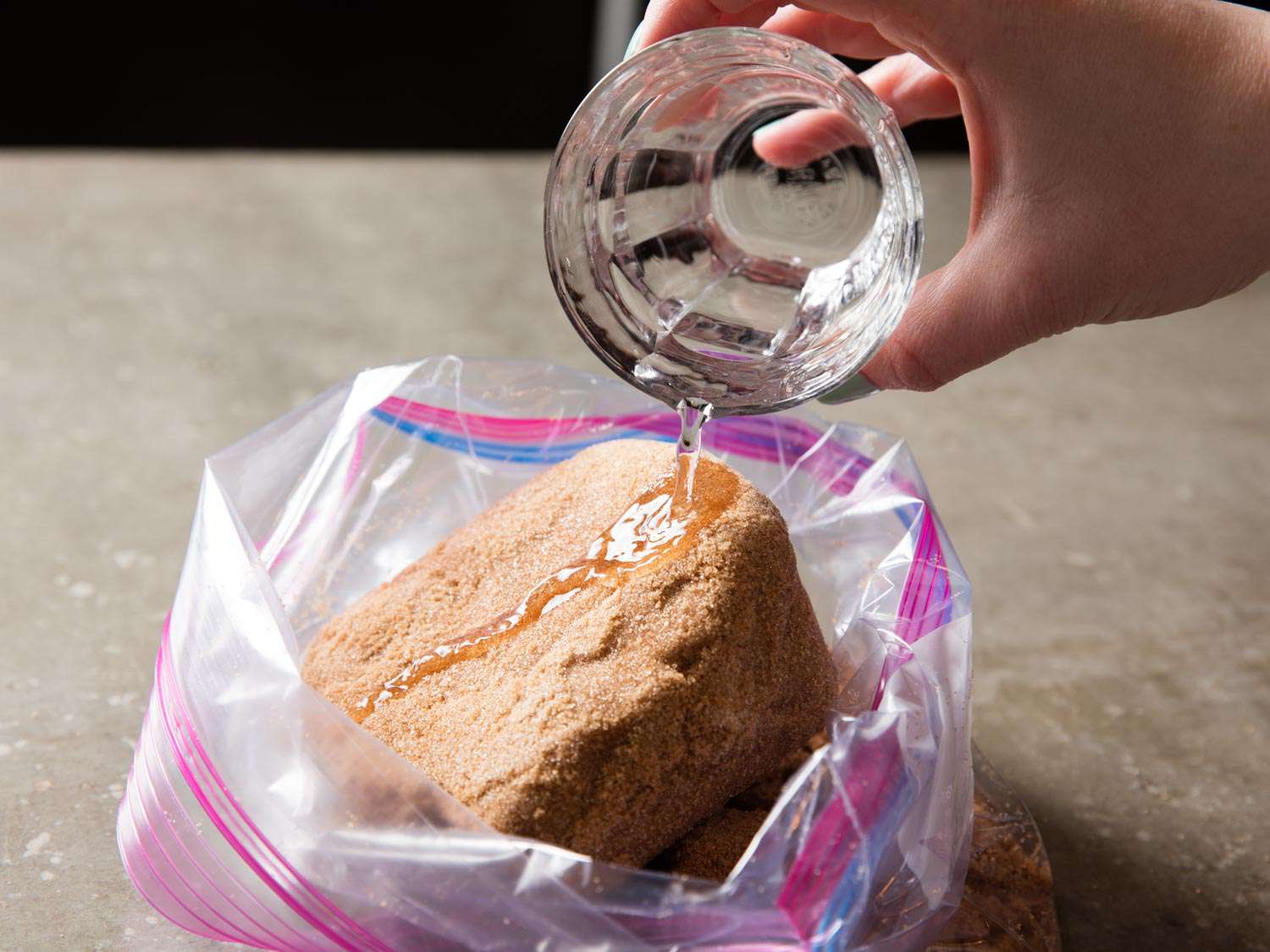 Adding water to a large, hardened lump of brown sugar in a zip-top bag.
