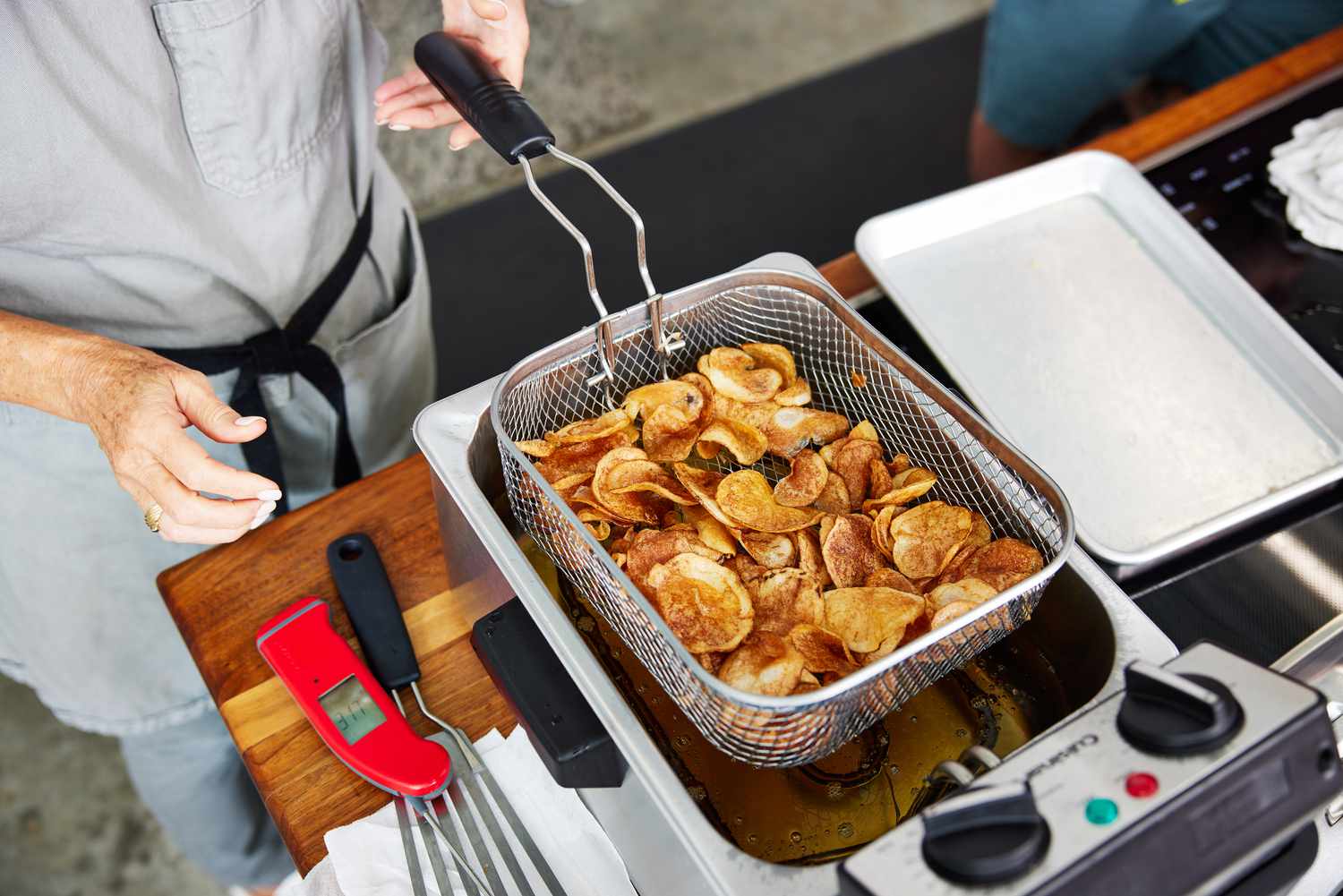 cooked potato chips being pulled out of a deep fryer