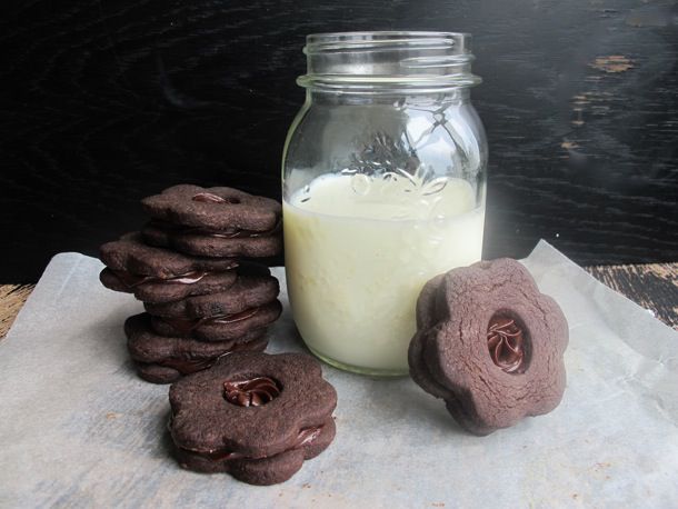 Chocolate shortbread sandwich cookies arranged around a pint-size canning jar of milk.