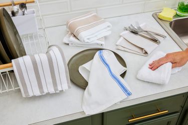 Numerous kitchen towels on a kitchen countertop.