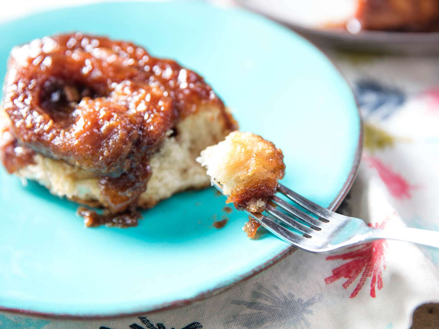 Fork piercing a piece of double-caramel sticky bun.
