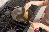 A person oils the bottom of the Misen 12 Inch Carbon Steel Wok