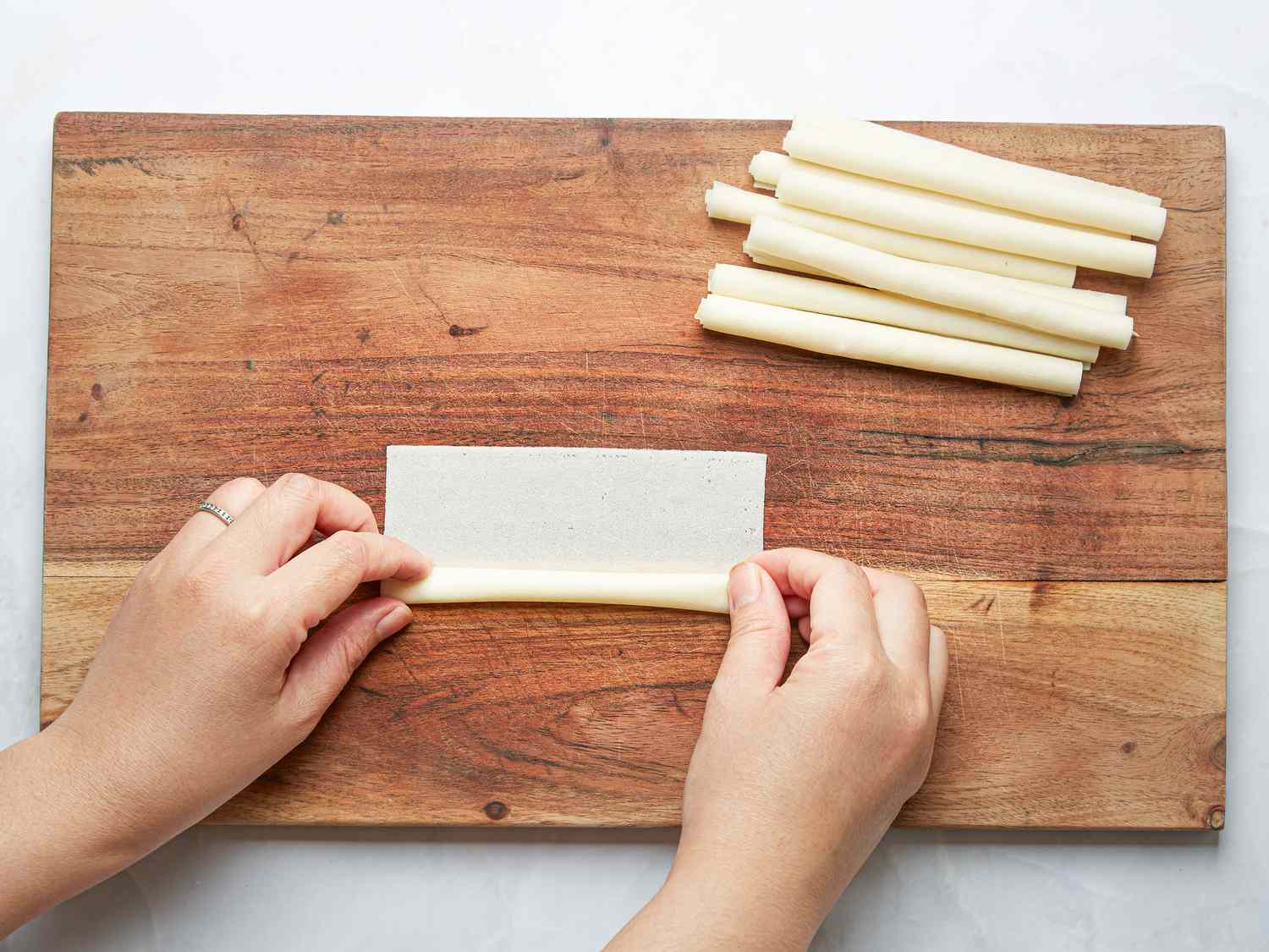 Overhead view of rolling wrappers into a cigar-shaped log